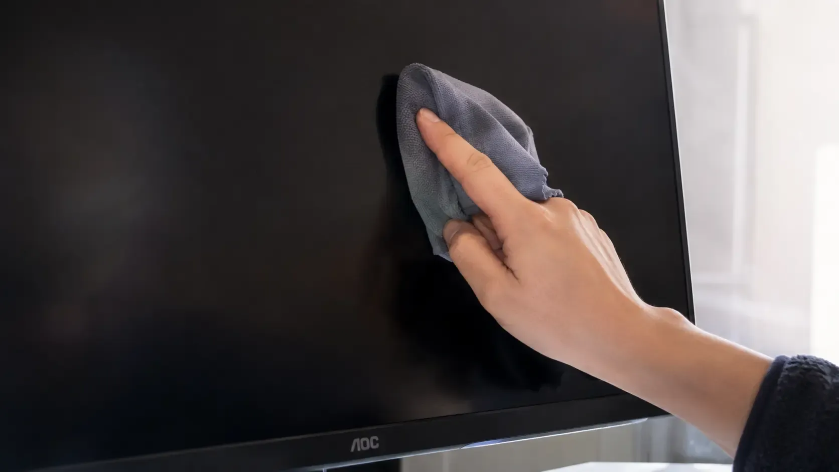 A folded microfiber cloth pressed gently against one spot on an LCD monitor